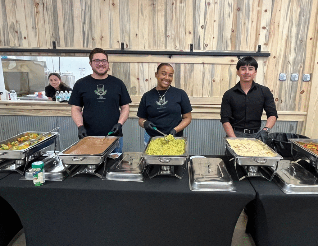 Workers standing behind a table of serving trays